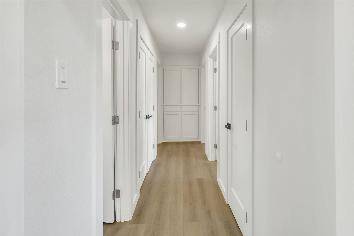 Hallway with built in shelving and cabinetry at the end